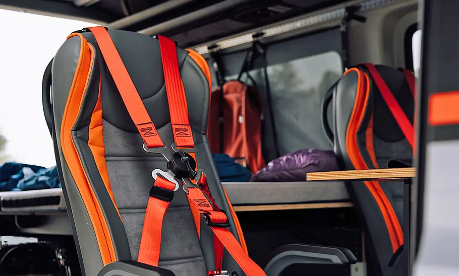 Innenraum des Torsus Terrastorm Camper mit Sportsitzen und orangen Vierpunktgurten.