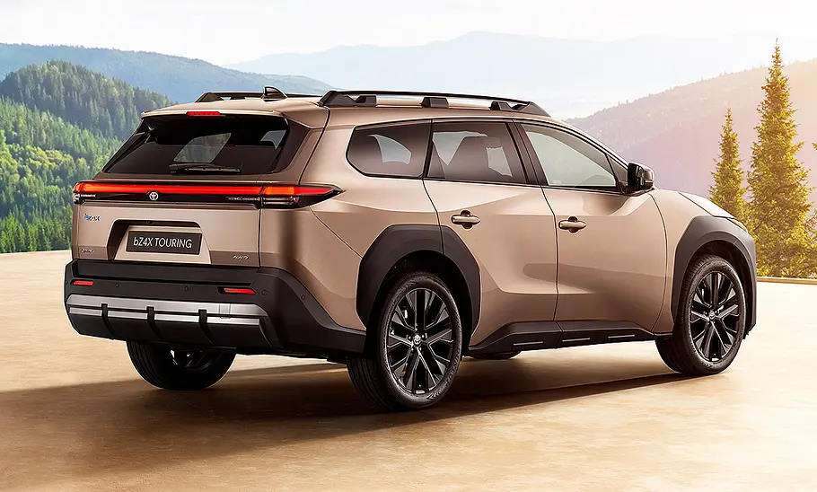 Der Toyota bZ4X Touring steht vor einem Waldpanorama, von hinten rechts fotografiert.
