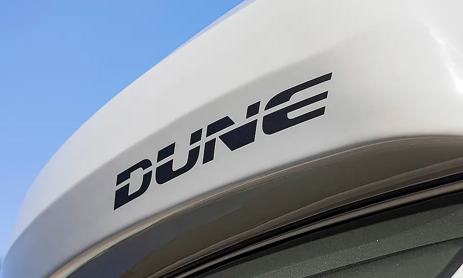 Die Außenaufnahme zeigt den Dune-Schriftzug des VW Grand California Dune (2025) im Detail.