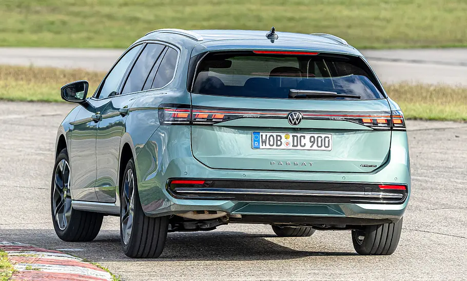 VW Passat Der VW Passat fährt durch eine Linkskurve. Von hinten fotografiert.