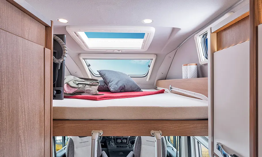 Die Innenaufnahme zeigt das Bett unterm Hochdach des Weinsberg Carabus 600 MQH.