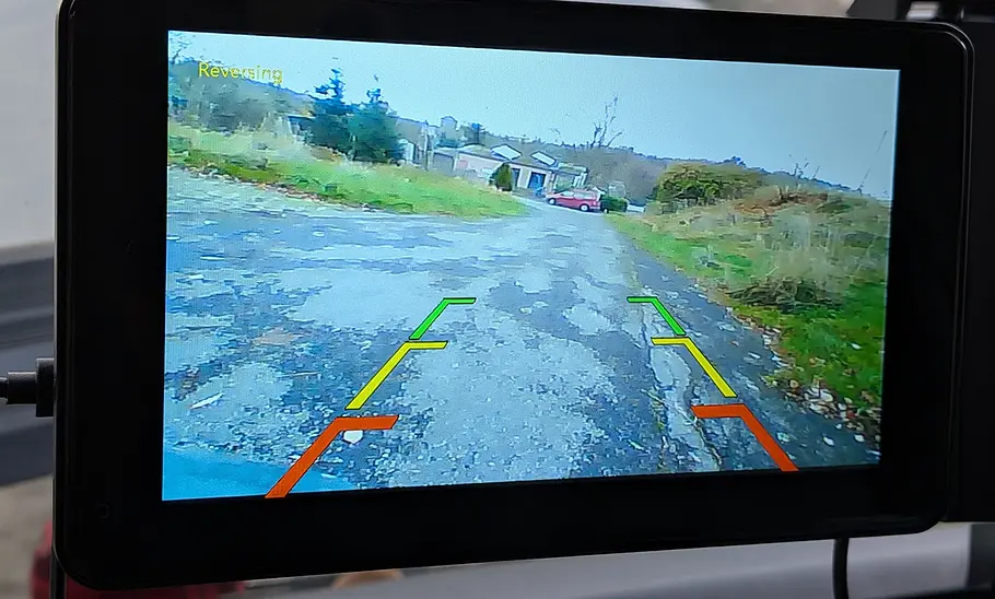 Das NFOIEIS Car Player 7 Zoll an einer Windschutzscheibe mit Bild der Rückfahrkamera, fotografiert von hinten.
