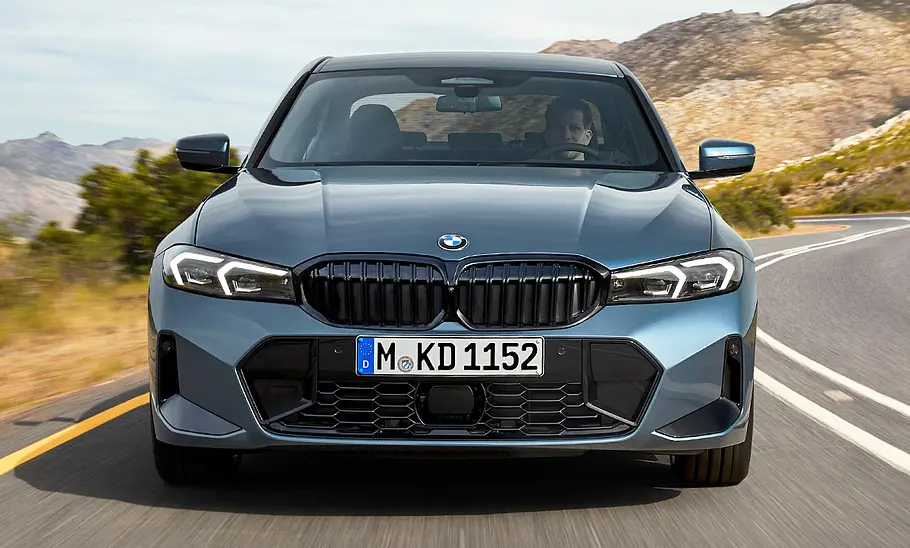 Das BMW 3er Facelift (2024) fährt auf einer Landstraße, von vorne fotografiert.