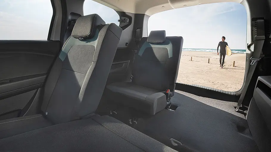 Das Dacia Jogger Facelift (2026) steht mit teilweise umgeklappten Sitzen und geöffneter Heckklappe an einem Strand, von innen fotografiert.