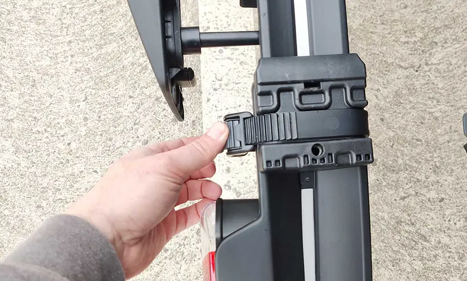 Thule-Fahrradträger für bis zu drei E-Bikes im Test Das Detailfoto zeigt die Hand eines Testers, der die Befestigungsratsche für die Fahrradfelge bedient.
