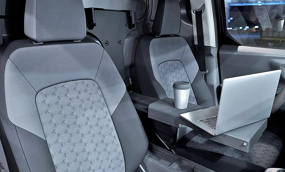 Auf der Mittelkonsole des Ford E-Transit Courier (2025) sind ein Laptop und ein Becher abgestellt.