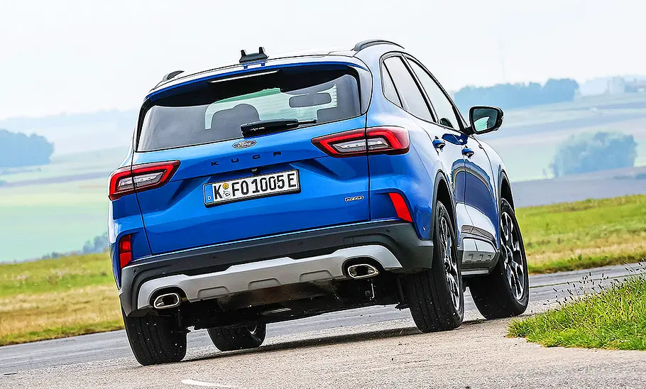 Ford Kuga Blick von schräg hinten auf den fahrenden Ford Kuga, der im sportlichen Fahrstil eine scharfe Kurve passiert.