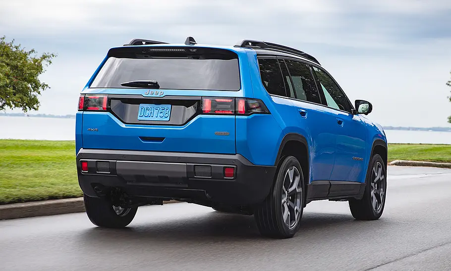 Der Jeep Cherokee fährt eine Küstenstraße entlang, von hinten rechts fotografiert.