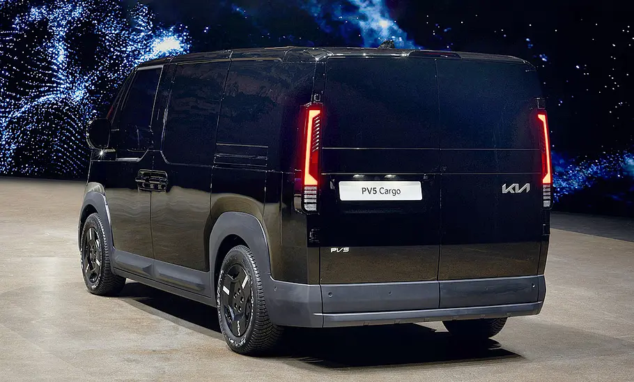 Kia PV5 Cargo (2025) Der Kia PV5 Cargo (2025) steht in Studioumgebung, von hinten links fotografiert.
