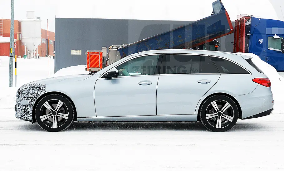 Das Mercedes C-Klasse T-Modell Facelift (2025) fährt als Erlkönig auf einer verschneiten Straße, von links fotografiert.