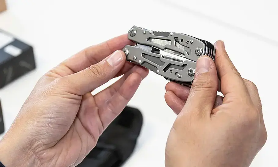 Prüferhände beim Begutachten eines Multitools, fotografiert von oben.