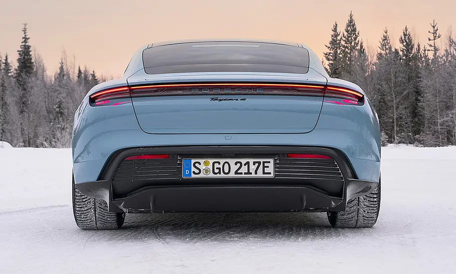 Das Porsche Taycan 4 Facelift (2025) steht im Schnee, statisch von hinten fotografiert.