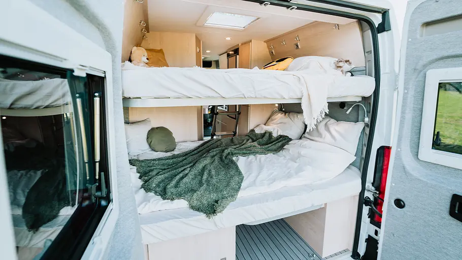 Clever Vans Vario Kids 600 (2026) Die Außenaufnahme zeigt die Betten und den Stauraum im Heck des Clever Vans Vario Kids 600 (2026) bei geöffneten Hecktüren.