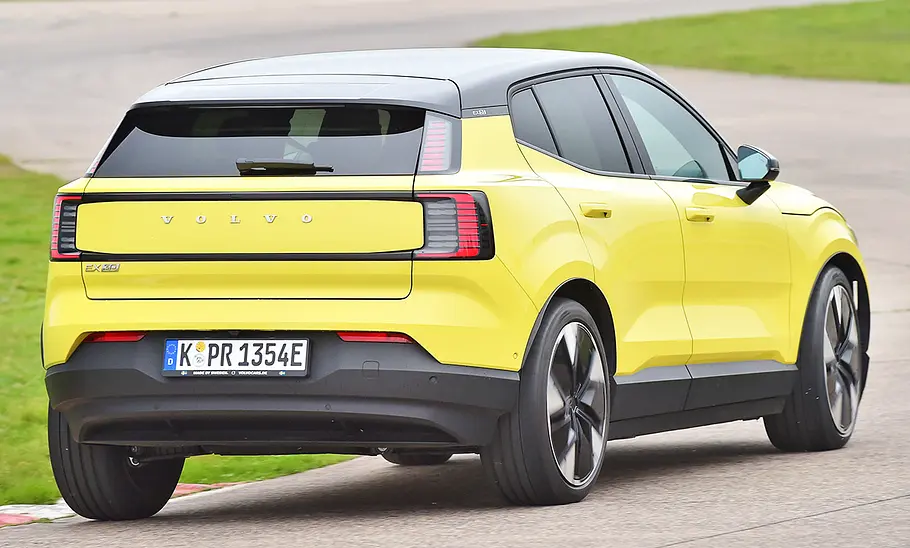 Blick von schräg hinten auf den fahrenden Volvo EX30.