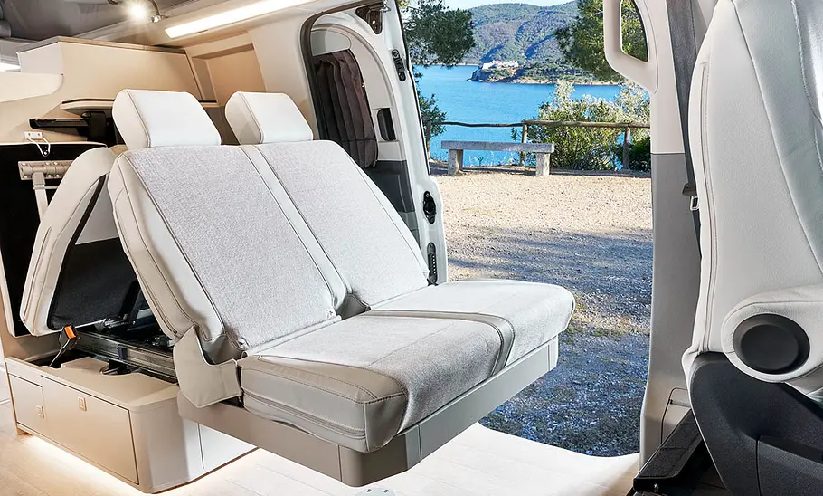 Blick auf die Sitzbank im Westfalia Kelsey (2025) mit schräg nach hinten geklappten Rückenlehnen. Die Schiebetür ist geöffnet.
