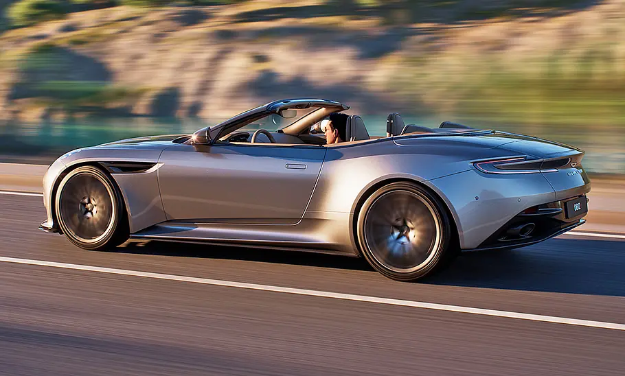 Aston Martin DB12 Volante (2023) Der Aston Martin DB12 Volante (2023) fahrend von schräg hinten/seitlich fotografiert.