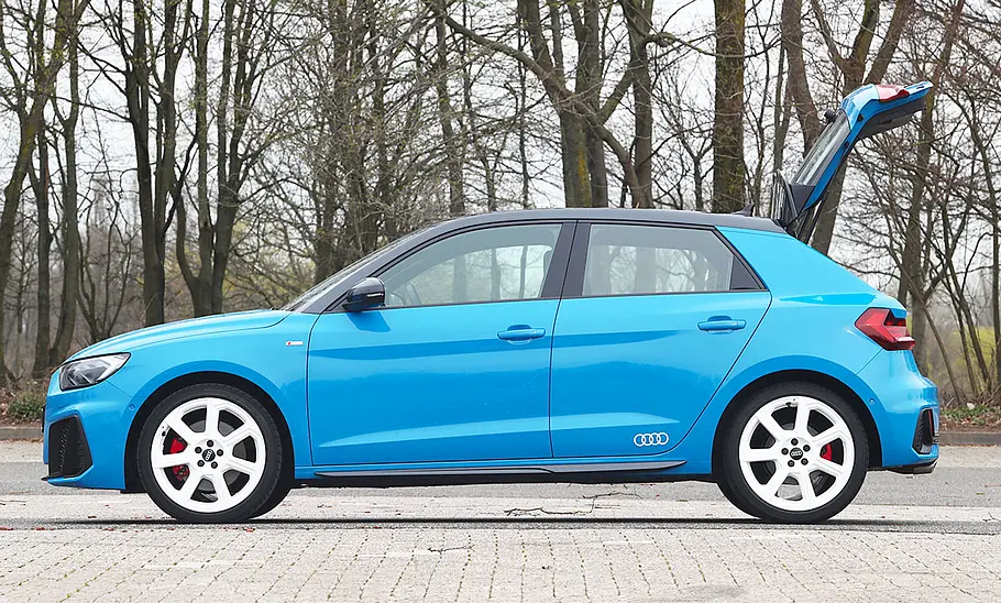 Audi A1 (2018) Der Audi A1 (2018) steht mit geöffneter Heckklappe auf einem Parkplatz, von links fotografiert.