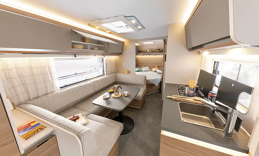 Dethleffs Nomad 560 FMK (2025) Blick durch den Wohnraum des Dethleffs Nomad 560 FMK (2025). Rechts der Küchenbereich, Links der Sitzbereich mit Tisch, weiter hinten ist der Schlafbereich zu erkennen.