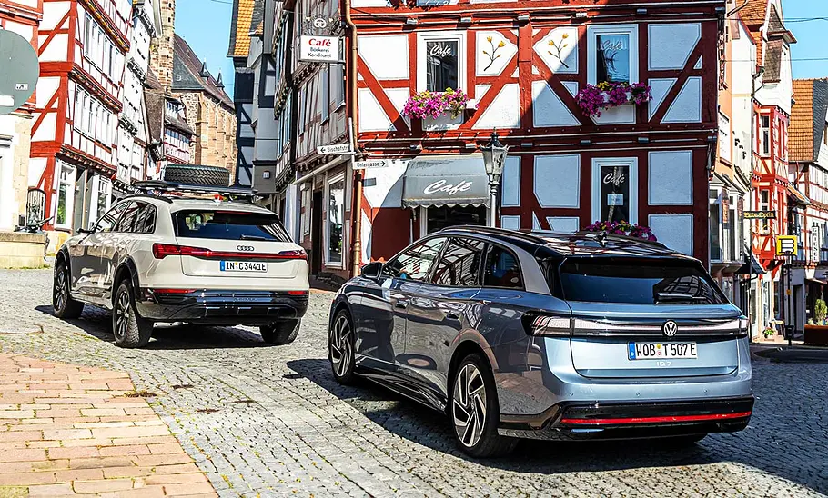 Audi Q8 e-tron Dakar Edition und VW ID.7 Tourer vor einem Fachwerkhaus.