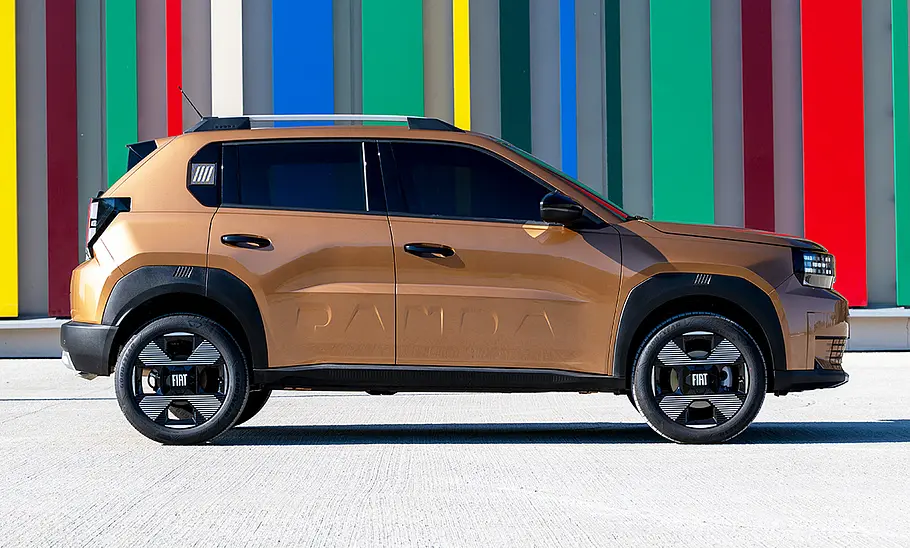 Der Fiat Grande Panda Hybrid (2025) steht vor einer bunt eingefärbten Wand, von rechts fotografiert.