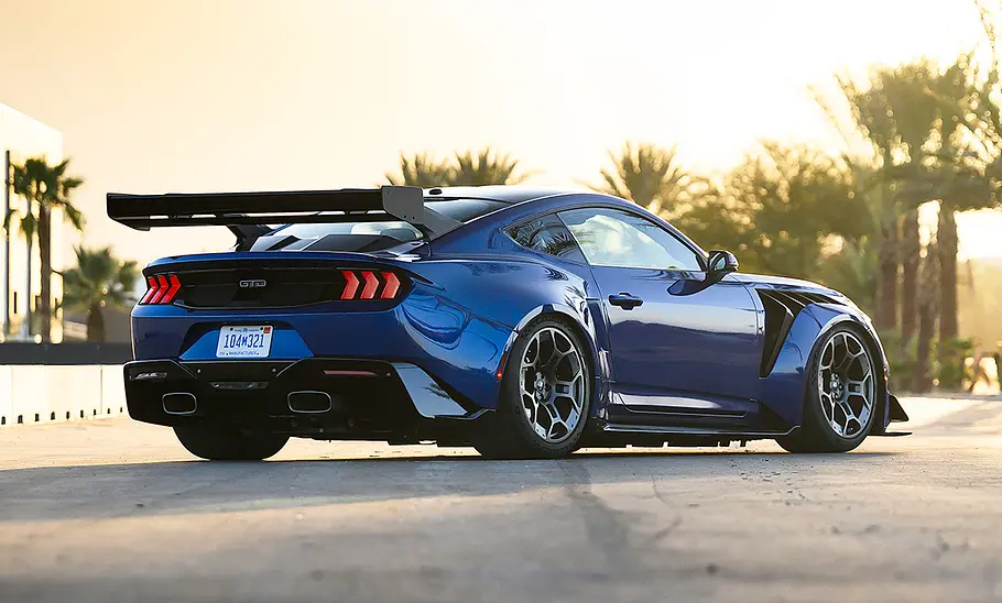 Der Ford Mustang GTD (2025) steht auf einer Straße, im Hintergrund Palmen. Von hinten rechts fotografiert.