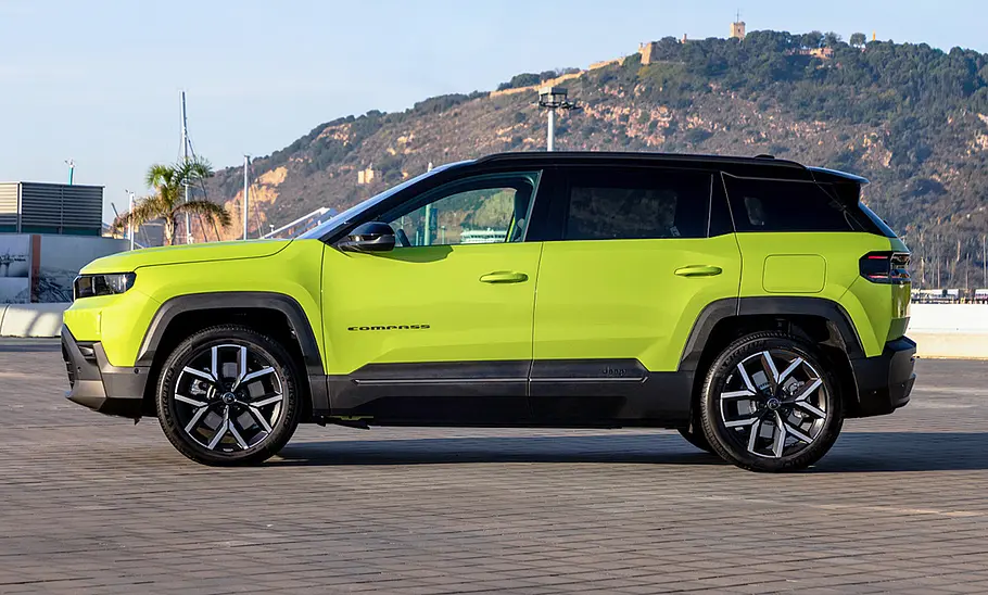 Der Jeep Compass steht vor einem hügeligen Panorama, von links fotografiert.