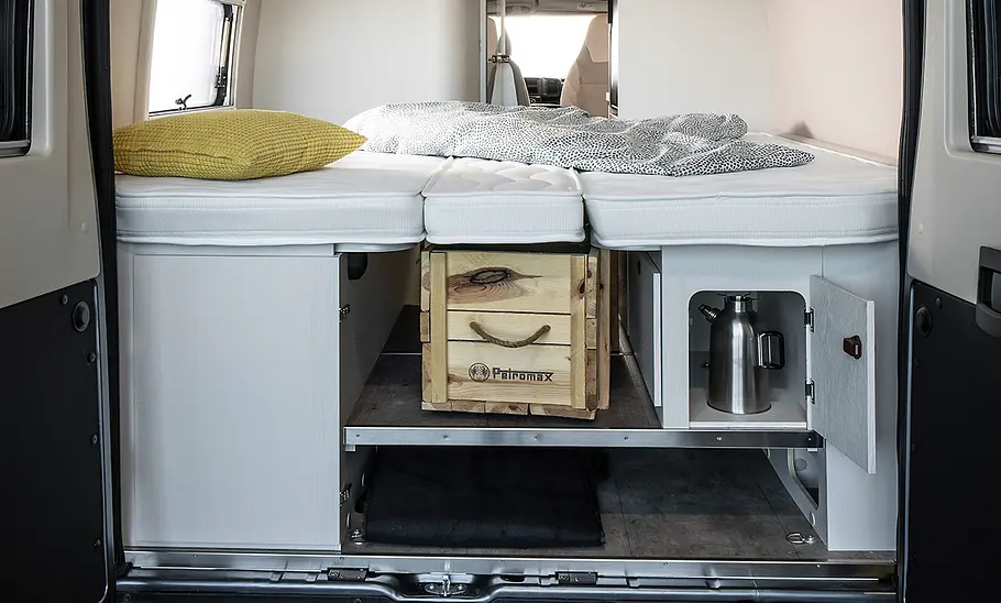 Blick ins Heck des Karmann Davis 620 LS (2025) durch die beiden geöffneten Hecktüren. Der Camper hat einen doppelten Boden, die Betten sind aufgebaut.
