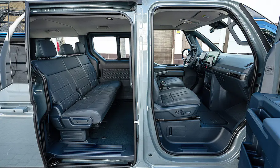 Der Innenraum des Kia PV5 Passenger (2025), durch die beiden geöffneten rechten Türen fotografiert.