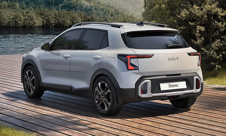 Kia Stonic GT-Line Facelift (2026) Kia Stonic GT-Line Facelift (2026) steht auf einem Platz am Wasser und bewaldeten Bergen. Ansicht von hinten.