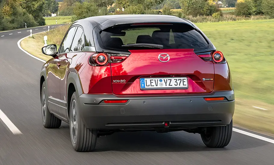 Mazda MX-30 e-Skyactiv R-EV (2025) Der Mazda MX-30 e-Skyactiv R-EV (2025) fährt auf einer Straße, von hinten fotografiert.