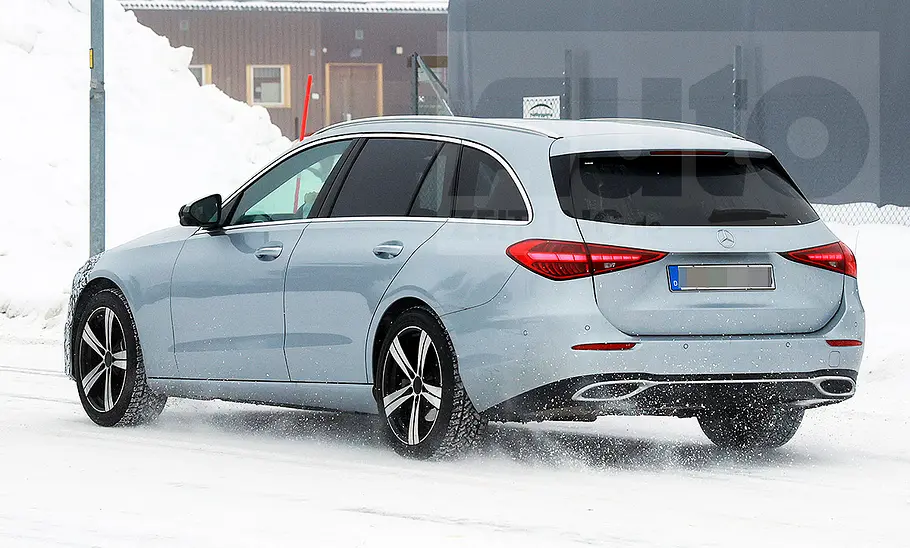 Das Mercedes C-Klasse T-Modell Facelift (2025) fährt als Erlkönig auf einer verschneiten Straße, von hinten  links fotografiert.
