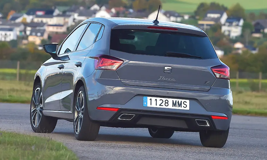 Der Seat Ibiza fährt durch eine Linkskurve, von hinten fotografiert.
