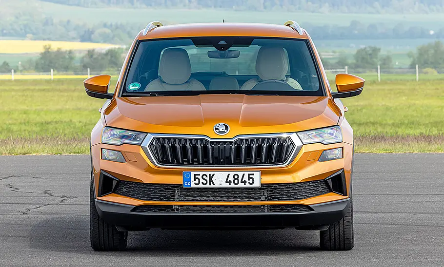 Skoda Karoq (2021) Der Skoda Karoq (2021) steht vor einer Wiese auf Beton, von vorne fotografiert.