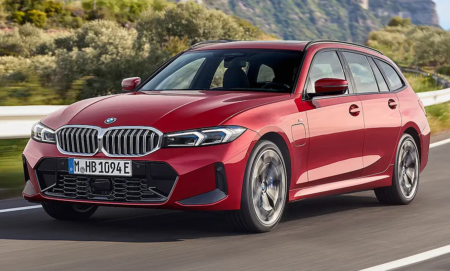 Das BMW 3er Touring Facelift (2024) fährt auf einer Landstraße, von vorne links fotografiert.