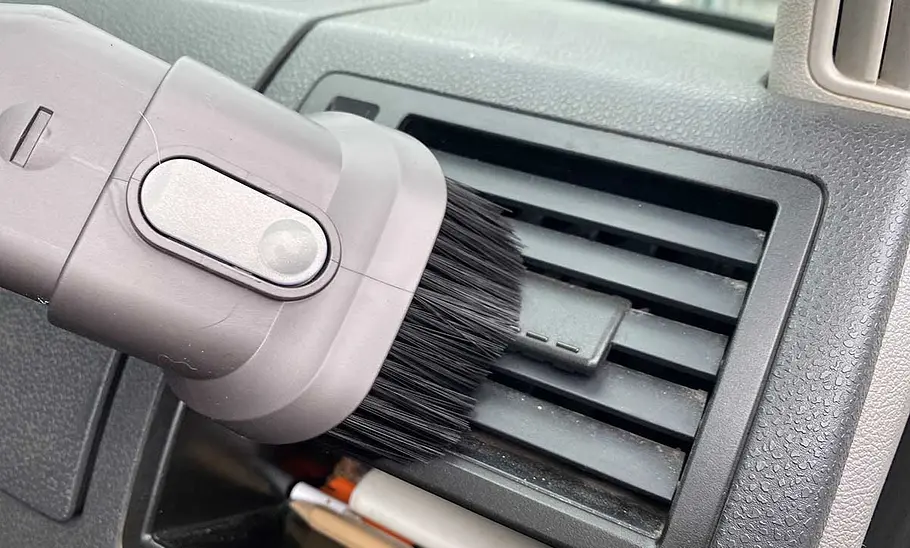 Die Detailaufnahme zeigt den Bürstenkopf des Dyson Akku-Staubsauger Car & Boat V8 beim Absaugen der Lamellen eines Luftauströmers.