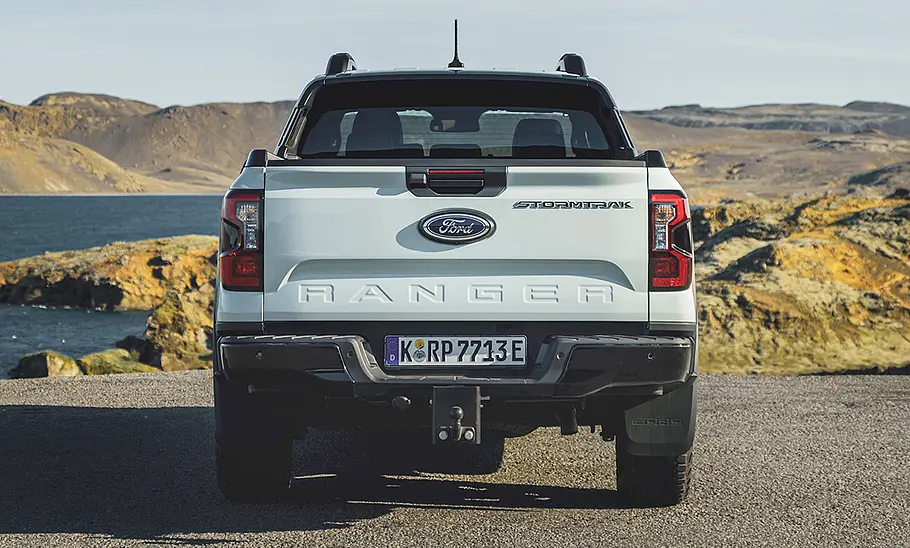 Der Ford Ranger Plug-in-Hybrid (2025) steht vor einem Bergpanorama, von hinten fotografiert.
