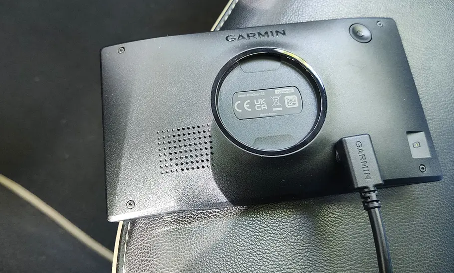 Rückseite des Garmin DriveSmart 66 MT-S mit Ladekabel, fotografiert auf dem Vordersitz eines Autos.