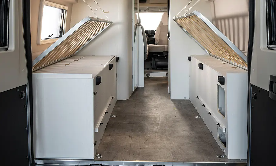 Blick ins Heck des Karmann Davis 620 LS (2025) durch die beiden geöffneten Hecktüren. Der Camper bietet das Maximum an Stauraum durch hochgeklappte Lattenroste und einen einfachen, tiefen Ladeboden.