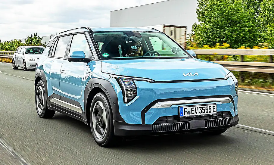 Blick von schräg vorne auf den fahrenden Kia EV3.