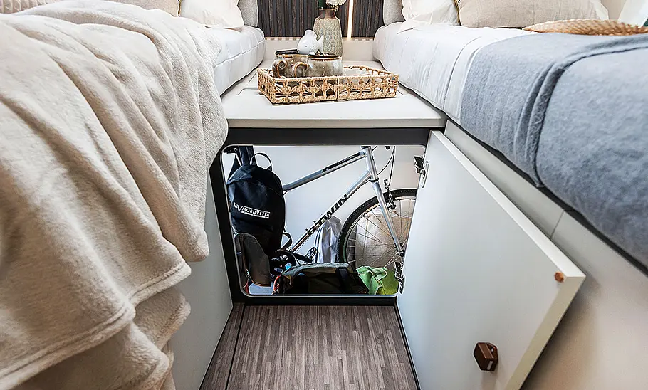 Mobilvetta Kea P86 (2025) Das Bild zeigt die Durchreiche zur Heckgarage zwischen den Einzelbetten des Mobilvetta Kea P86 (2025).