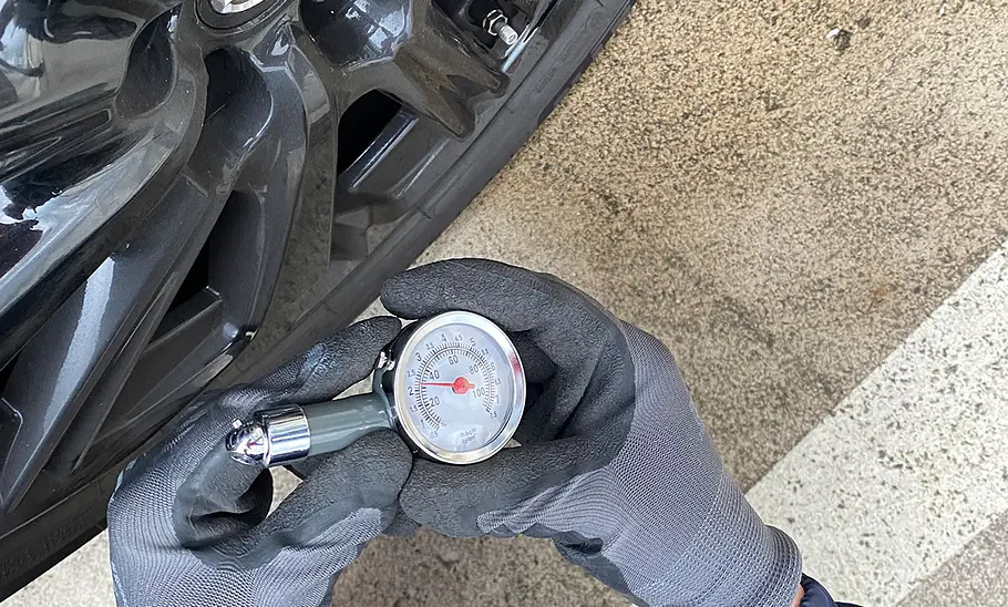 WHKM Dial Tire Gauge im Test Testerhände mit WHKM Dial Tire Gauge beim Prüfen des Reifendrucks, fotografiert von oben.