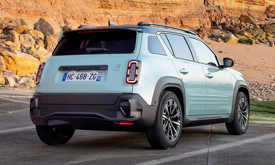 Der Renault 4 E-Tech Electric (2025) steht vor einem Felspanorama, von hinten rechts fotografiert.