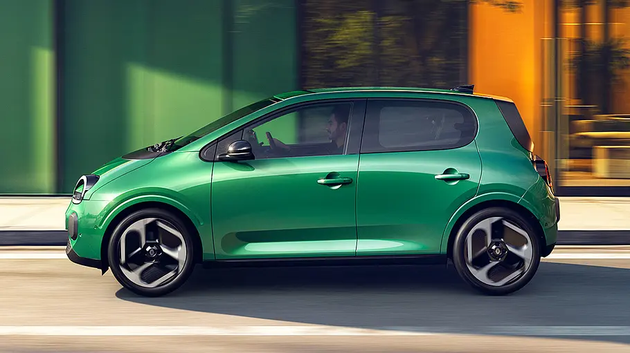 Renault Twingo E-Tech Electric Der Renault Twingo E-Tech Electric fährt durch eine Stadt, von links fotografiert.