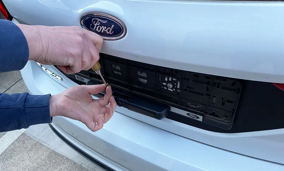 Tester beim Fixieren einer Schraube an der Primaster Solar Rückfahrkamera, die an einen Ford Fiesta montiert wurde.
