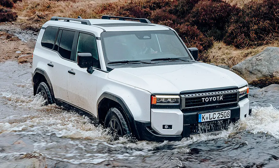 Toyota Land Cruiser (2024) Der Toyota Land Cruiser First Edition (2024) fährt durch Wasser, von schräg vorne fotografiert.