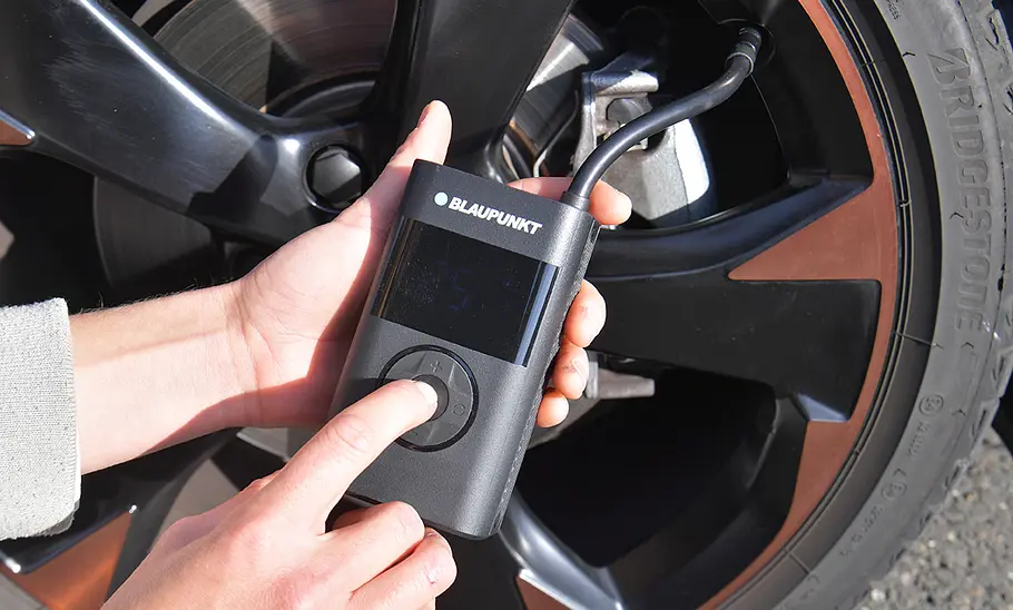 Testerhände mit Blaupunkt TPM 124, fotografiert von der Seite. Akku-Luftpumpe Blaupunkt TPM 124 im Test
