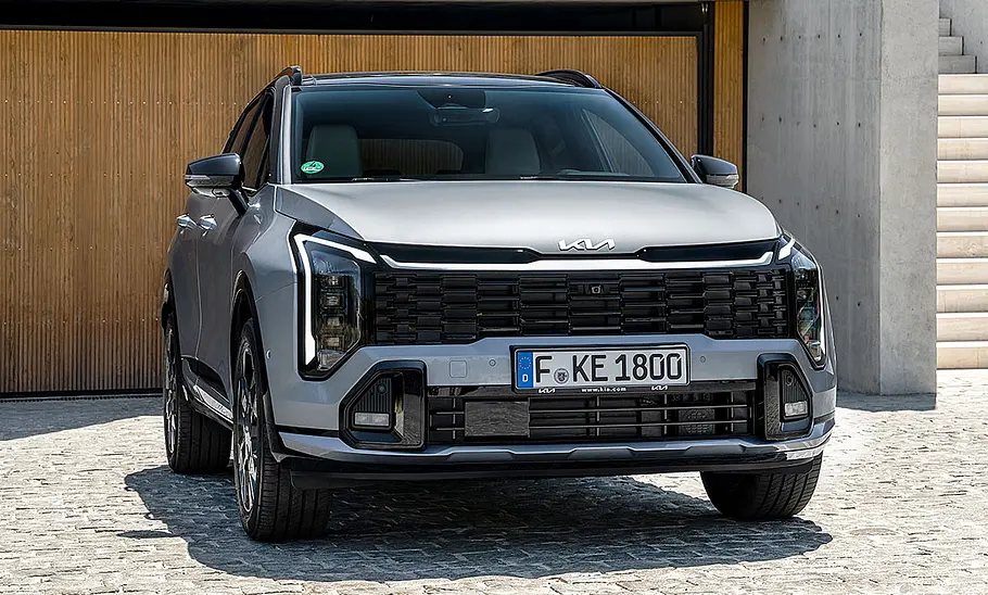 Kia Sportage (2025) Der Kia Sportage (2025) parkt vor einem Haus, von vorne fotografiert.