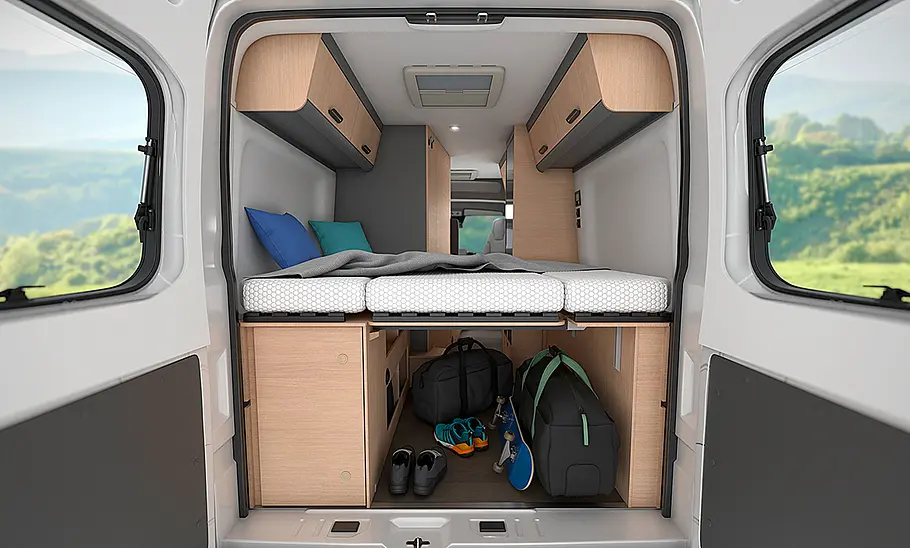 Sunliving V 60 SP (2025) Das Bild zeigt das Heckbett des Sunliving V 60 SP (2025) durch die geöffneten Hecktüren fotografiert. In der Heckgarage unter der Liegefläche ist Gepäck eingeladen.