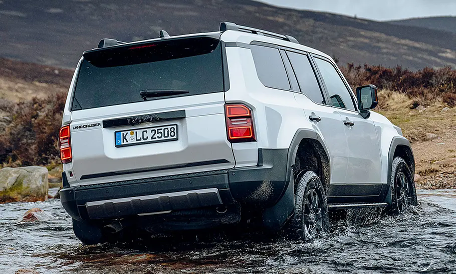 Toyota Land Cruiser (2024) Der Toyota Land Cruiser First Edition (2024) fährt durch Wasser, von schräg hinten fotografiert.