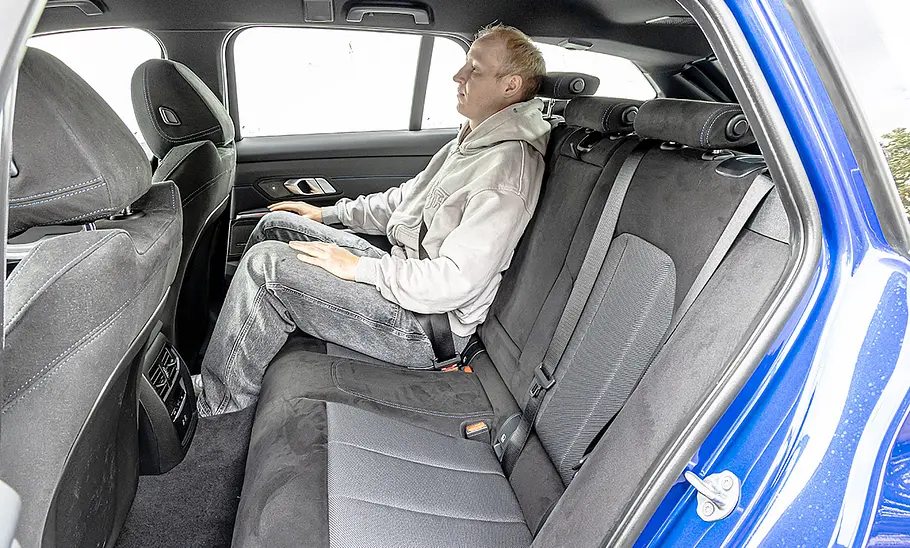 BMW 3er Touring Eine Person sitzt auf dem rechten Rücksitz des BMW 3er Touring. Durch die hintere, linke Tür fotografiert.